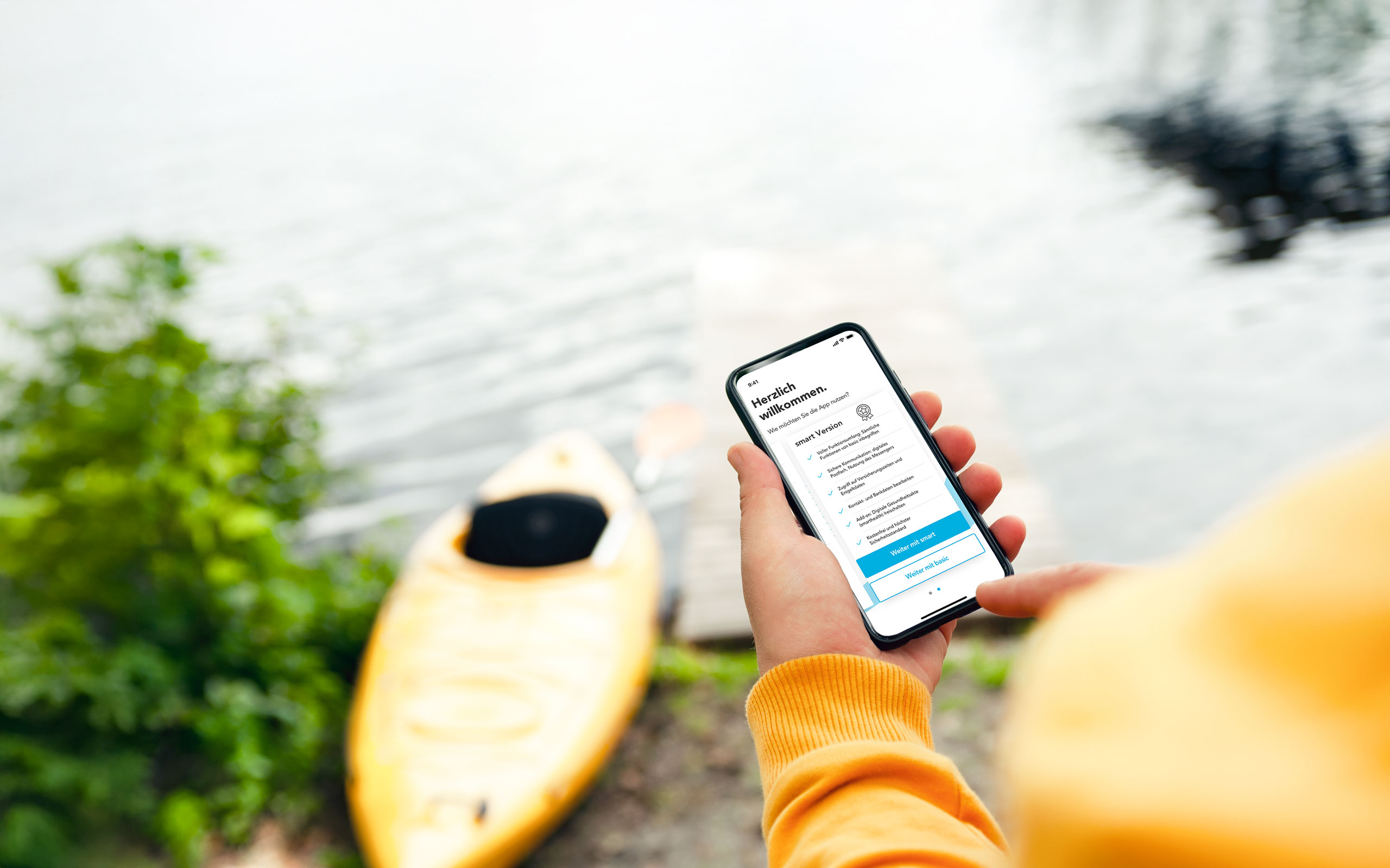 Hand mit HEK Service-App auf dem Handy und gelbem Kanu